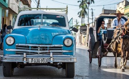 Blue American Vintage Car parked on the street with horse-drawn carriage
