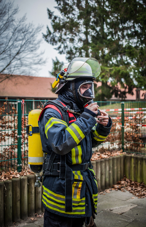 Firefighter outdoor in action with oxygen bottle and respiratory protection mask - HDRのeditorial素材