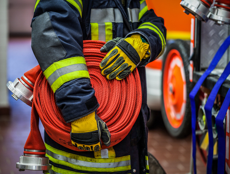 HDR - Fireman in action with a rolled firehose on the emergency vehicleの写真素材