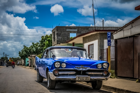 HDR - Blue american Dodge classic car with white roof parked on the side street before a blue old building in Santa Clara Cuba - Cuba Series Reportのeditorial素材