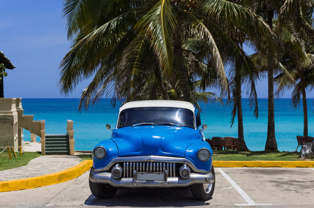 American blue classic car with white roof parked under palms on the beach at Varadero Cuba series Cuba Reportageの写真素材