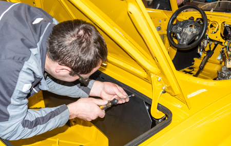 Car mechanic screws car parts together again after restoration - Serie Repair Workshopの写真素材