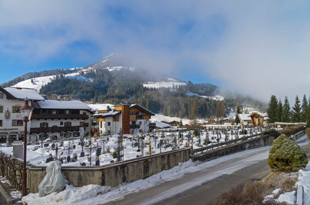 Cemetery in Kirchberg in Tyrol, Austria. Sunny winter morning, low clouds.のeditorial素材