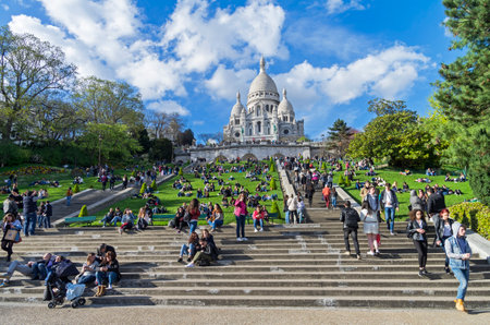PARIS, FRANCE - APRIL 1, 2017: Tourists on the hillside of Montmartre on the background of the Sacre-Coeur basilica. The beginning of April. Paris, France.のeditorial素材