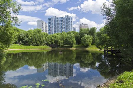 A small pond in the south-west of Moscow, Russia. Reflection of buildings in the water surface. Sunny day in July.の写真素材