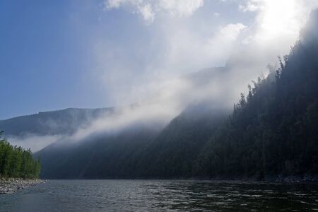 Morning on the mountain river. Rising night fog turns into light cloud cover. The Oka Sayan River in the Orkho-Bom Gorge. East Sayan, Buryatia, Siberia, Russia.の写真素材