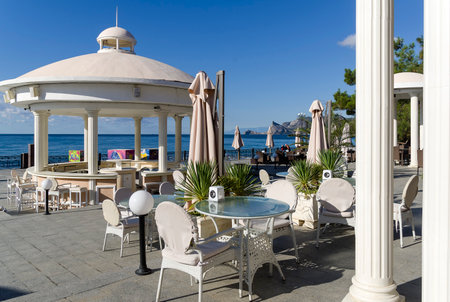 Sudak, Crimea - September 23, 2019: An empty cafe on the seaside promenade of the resort town in the early sunny morning. September.のeditorial素材