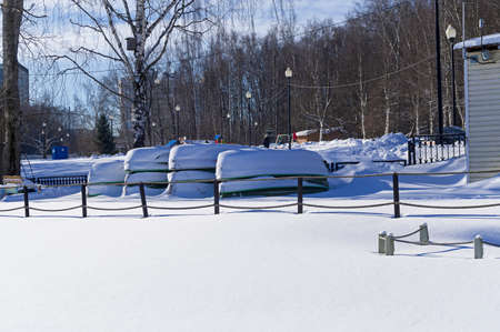 Upside-down snow-covered boats at a boat station closed for the winter. Teplostanovsky Forest Park,...