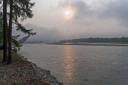 River Oka at the village of Orlik. The sky is covered with smoke from forest fires brought from Yakutia. Buryatia, Siberia, Russia.の写真素材