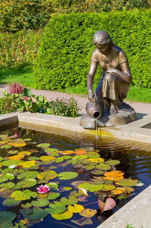 MOSCOW, RUSSIA - September 24, 2023: Bronze sculpture of a girl pouring water from a jug - fountain in the park. Large rose garden in Sokolniki Park, Moscow, Russia. Sunny day in the second half of September.のeditorial素材