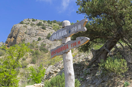 A sign at a fork in the trail on the slope of Mount Ai-Georgiy, indicating directions to the top of the mountain and to the spring, and the distances to them. The trail is part of the "Big Crimean Trail" project. Sudak, Crimea, April.の写真素材
