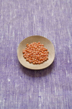 Close-up view of Organic hulled Red small Lentils in a wooden plateの写真素材