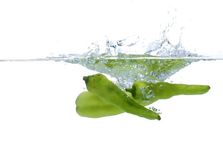 green chilli thrown in water with white backgroundの写真素材