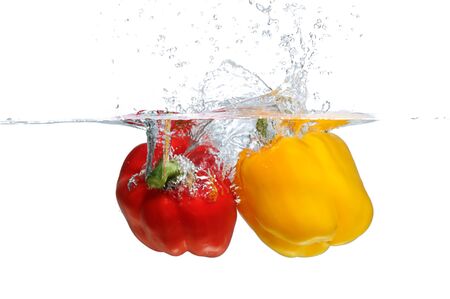 Fresh yellow and red Bell Pepper splashing into waterの写真素材