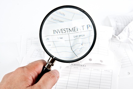 Close up stack of investment Spreadsheets and Magnifying Glassの写真素材