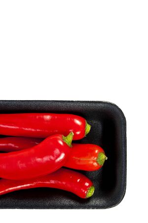 Fresh red hot pepper with black plate on a white background and blank text copy spaceの写真素材