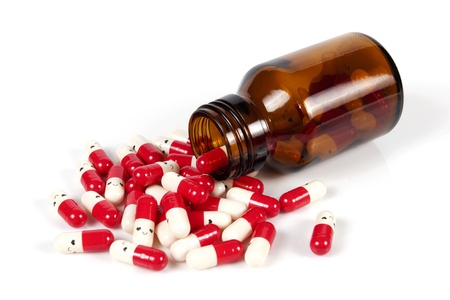 Open happy pill bottle with medicine spilling out of it isolated on whiteの写真素材