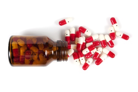 Open happy pill bottle with medicine spilling out of it isolated on whiteの写真素材