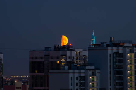 moon in night sky over the buildings of big cityの写真素材