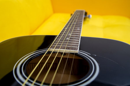 Acoustic guitar on yellow sofa in the living room, close up