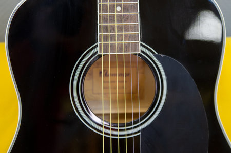 Acoustic guitar on a yellow background. Close-up, selective focus.