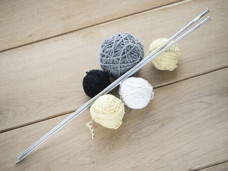 Image of wool balls and needls on wood background.