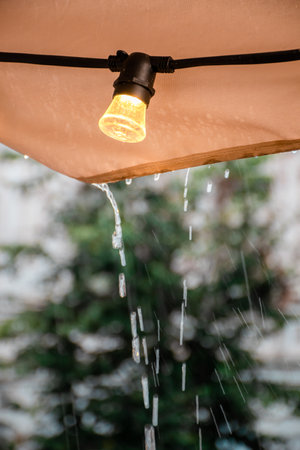 On a rainy summer day, an electric light bulb lights up on the roof of the cafe.