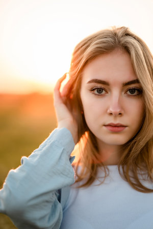 Woman in Field Adjusting Hair at Sunsetの写真素材
