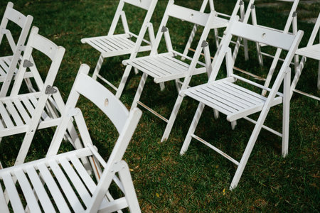 Empty White Folding Chairs Arranged on Grassの写真素材