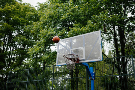 Basketball Approaching Hoop on Outdoor Courtの写真素材