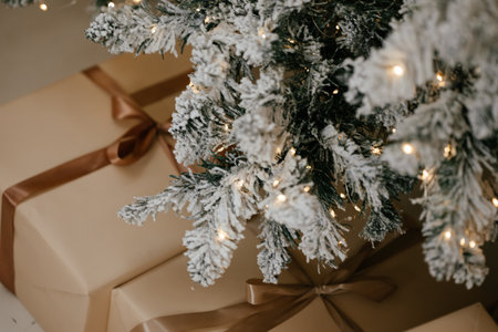 Christmas Presents Under Snowy Christmas Tree with Lightsの写真素材
