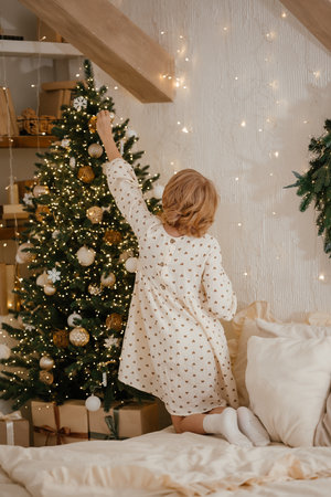 Child Decorating Christmas Tree in Cozy Roomの写真素材