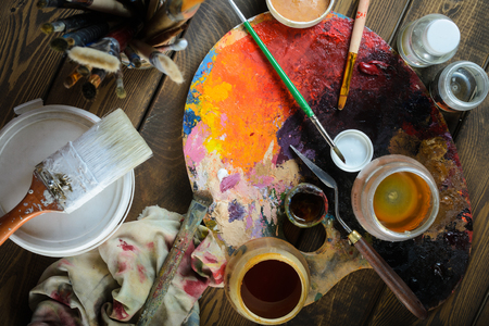 Paints, brushes, palette on a dark wooden backgroundの写真素材