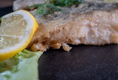 Dish of fish fillet with greens and lemon