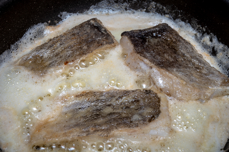 girl cooks fry fish in the kitchenの写真素材