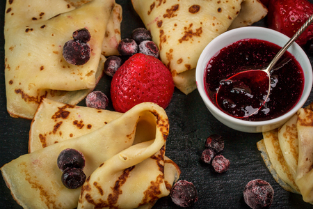 Russian pancakes with jam, black currant and strawberriesの写真素材