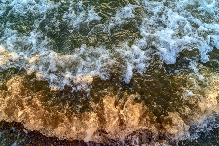 Sea foam on small stones on the sea beach close upの写真素材