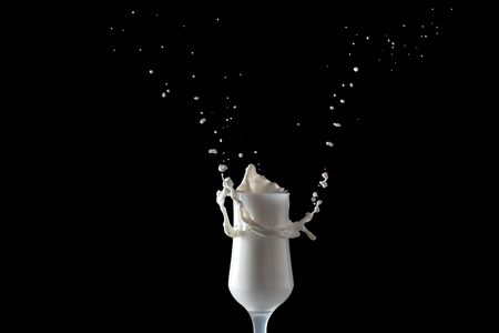 Milk shake splashes from a glass. Isolated image on black background.の写真素材