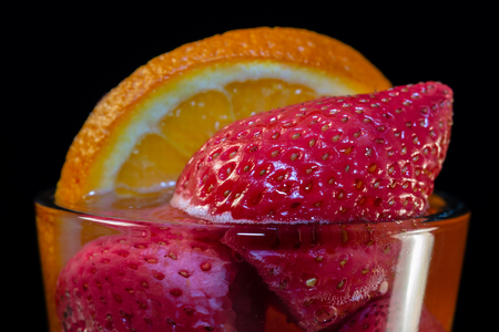 Strawberries with orange in a glass of waterの写真素材