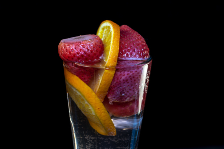 Strawberries with orange in a glass of waterの写真素材