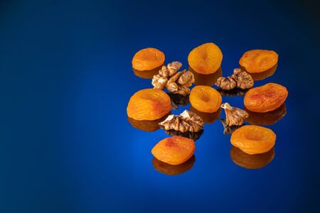 Walnuts and dried apricots on a gradient blue background close-up.の写真素材