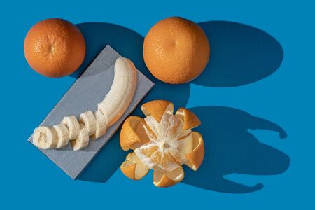 Oranges and bananas on a blue background. View from above.の写真素材