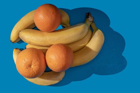 Oranges and bananas on a blue background. View from above.の写真素材
