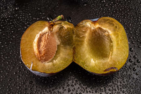 Ripe plums with water drops on a black backgroundの写真素材