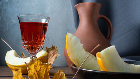 Still life with sliced melon, a clay jug of wine and autumn leavesの写真素材