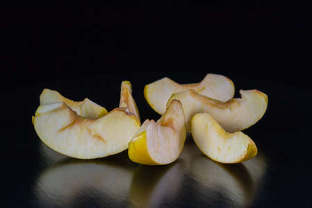 Yellow apple, cut into slices, on a black background.の写真素材