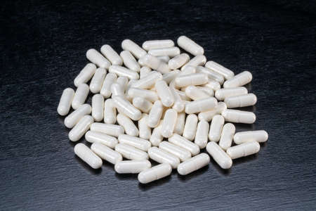 White capsules with medicine on a black background.