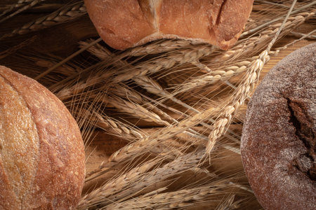 Three loaves of bread and ears of wheat on a black background