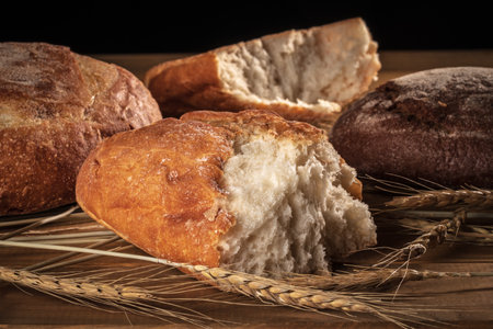 Three loaves of bread and ears of wheat on a black background