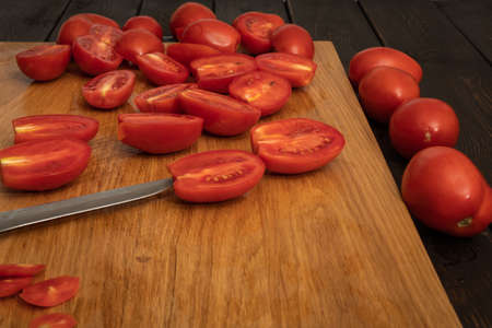 Tomatoes cut in half lie on a wooden boardの写真素材
